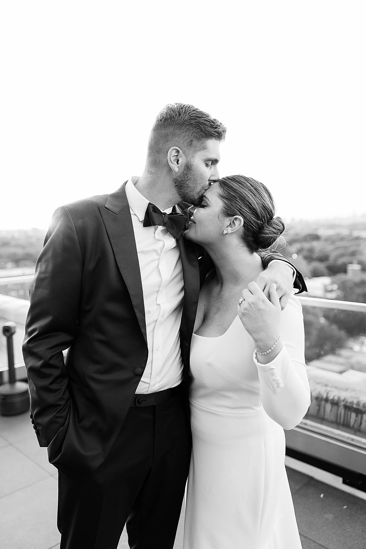 Black and white photo of man kissing woman on head