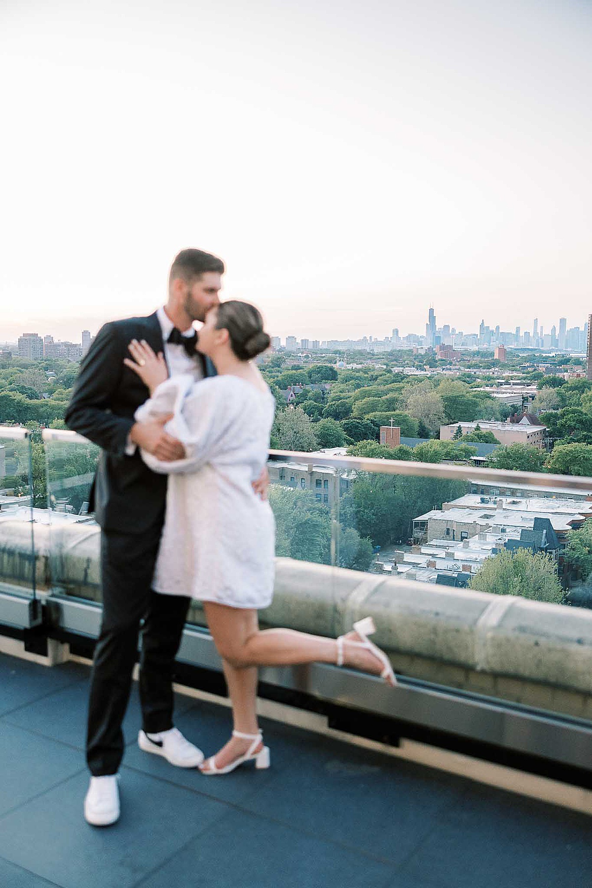 Woman kicks leg in air on balcony with Chicago in background