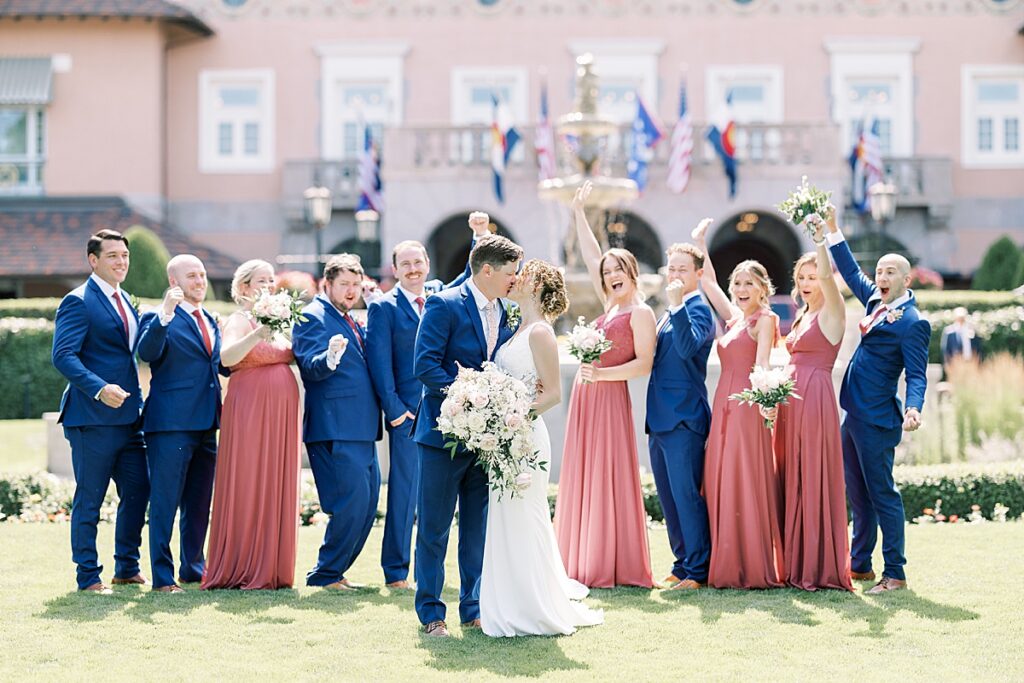 Couple kissing with wedding party cheering behind them