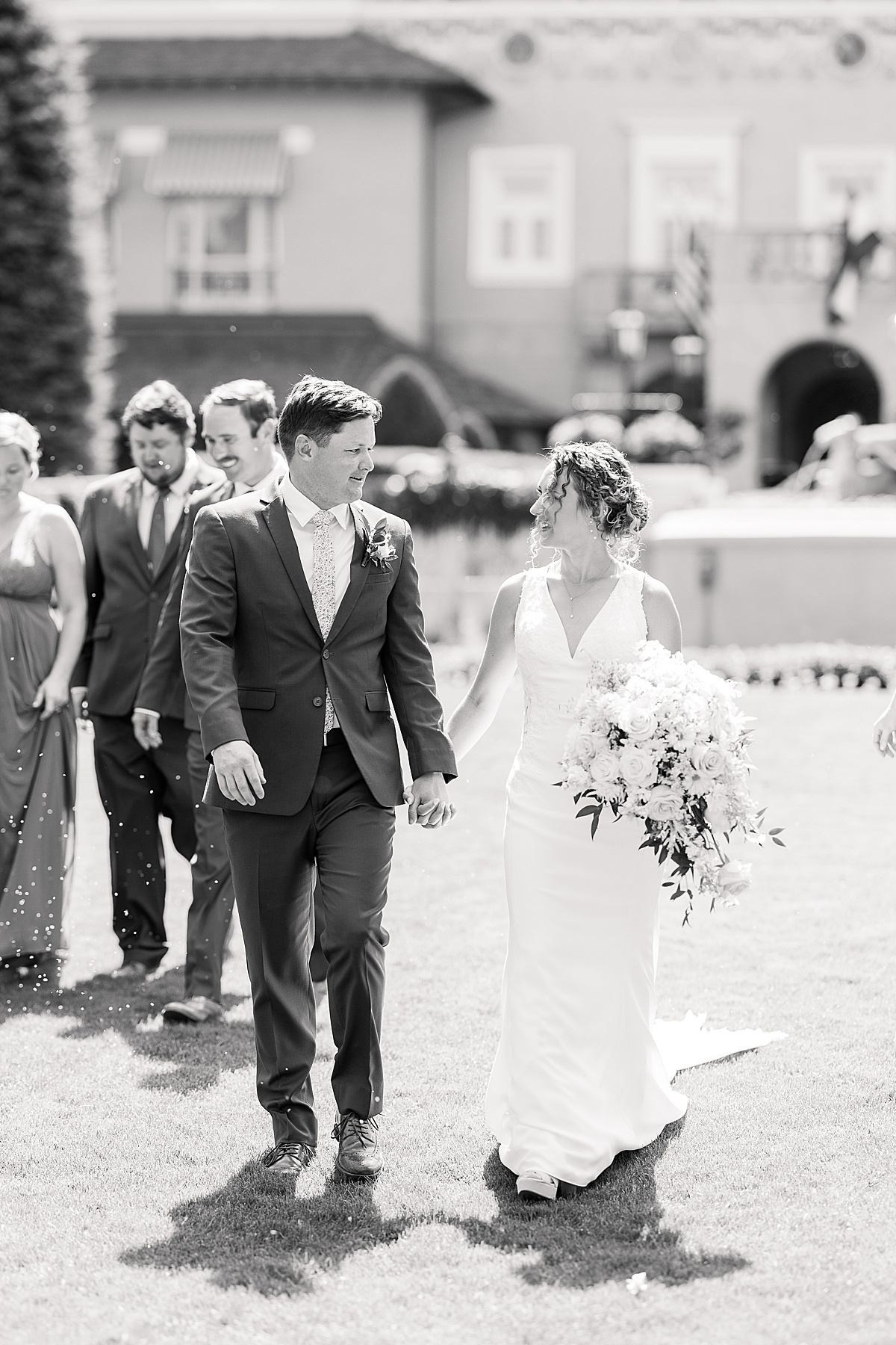 Black and white photo of wedding couple walking on lawn