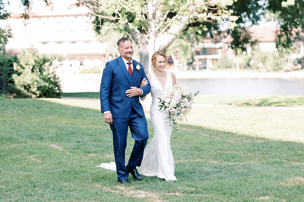 Father in blue suit walking bride down the aisle