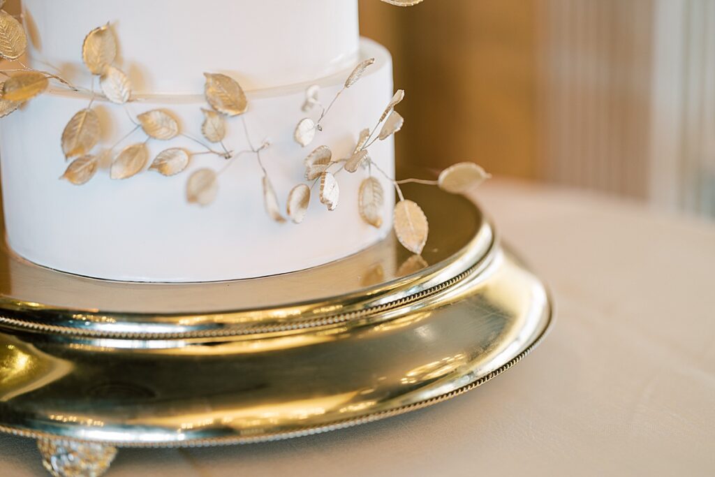 White wedding cake with gold leaves against a gold background