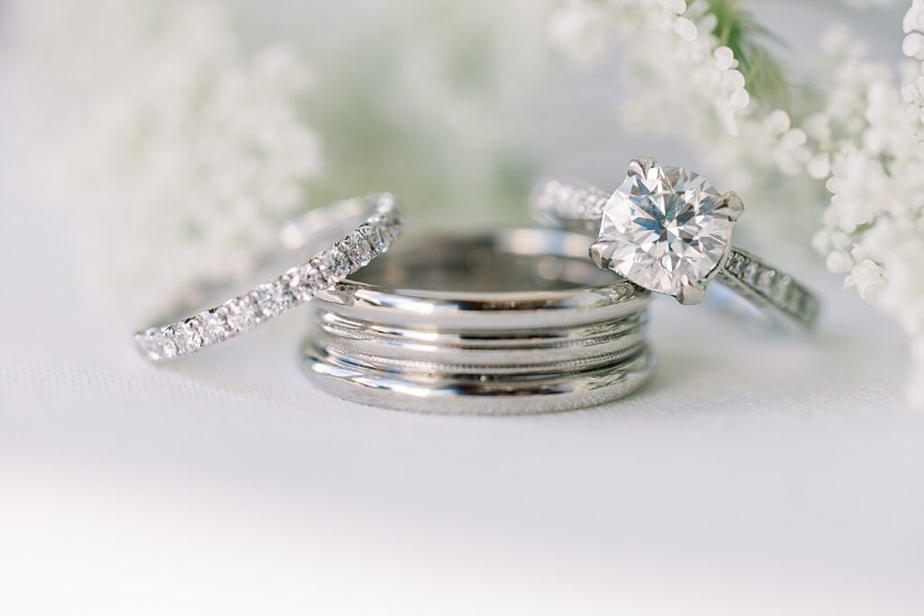 Tacori wedding rings on white mat with white flowers in the background