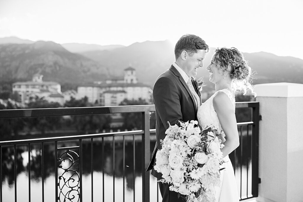 Black and white image of bride and groom laughing at each other on balcony