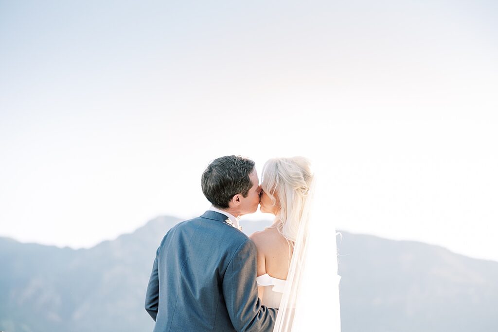 Bride and groom kissing in front of mountains