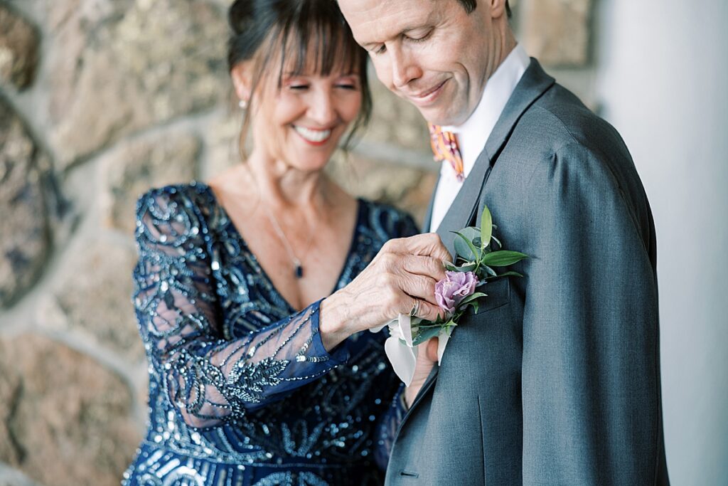 Woman in blue dress pinning boutonniere on groom