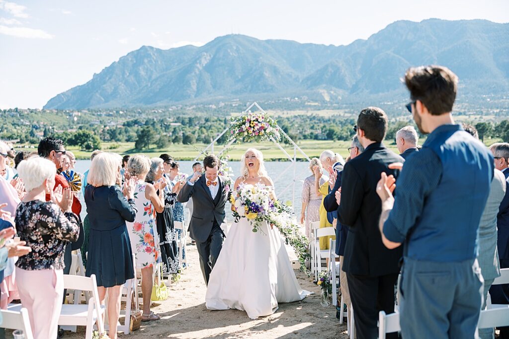 Smiling couple walking down ceremony aisle