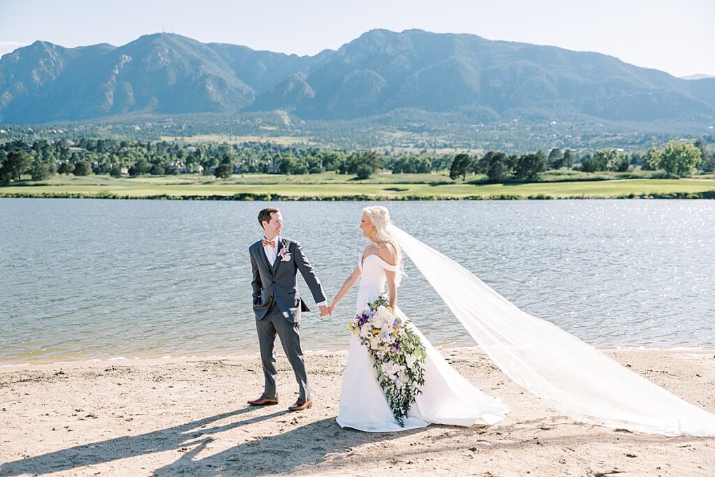 Bride with long veil walking on beach