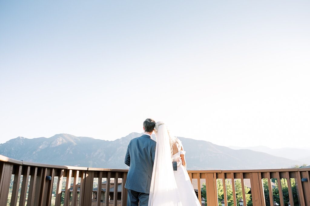 Couple snuggling looking at mountains on wedding day