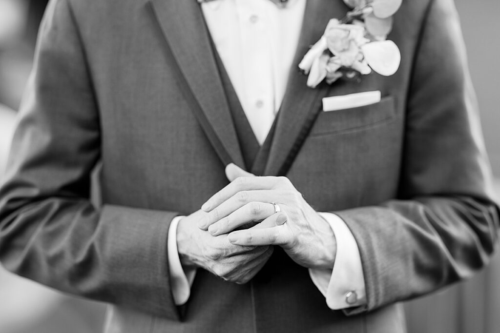 Black and white photo of groom adjusting his wedding ring