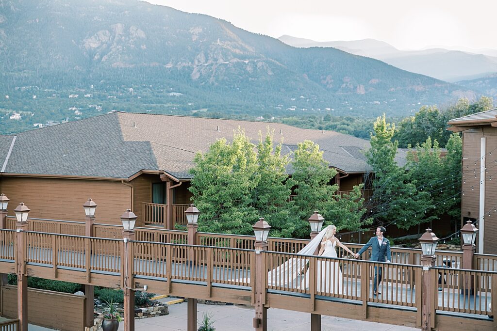 Couple walking on long wooden bride in front of mountains