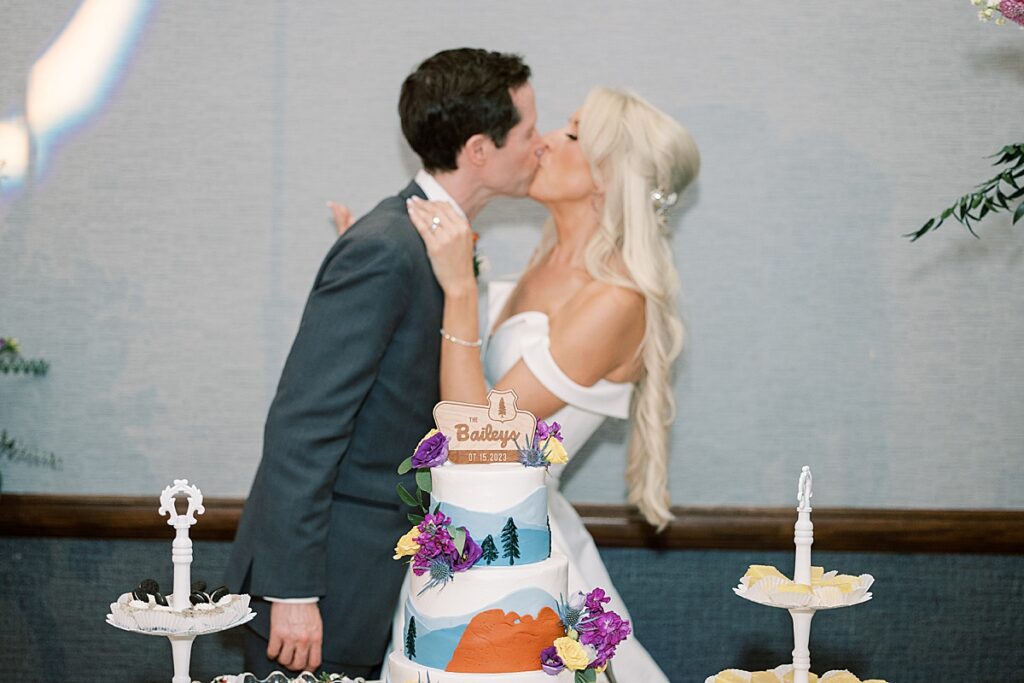 Couple kissing behind colorful wedding cake