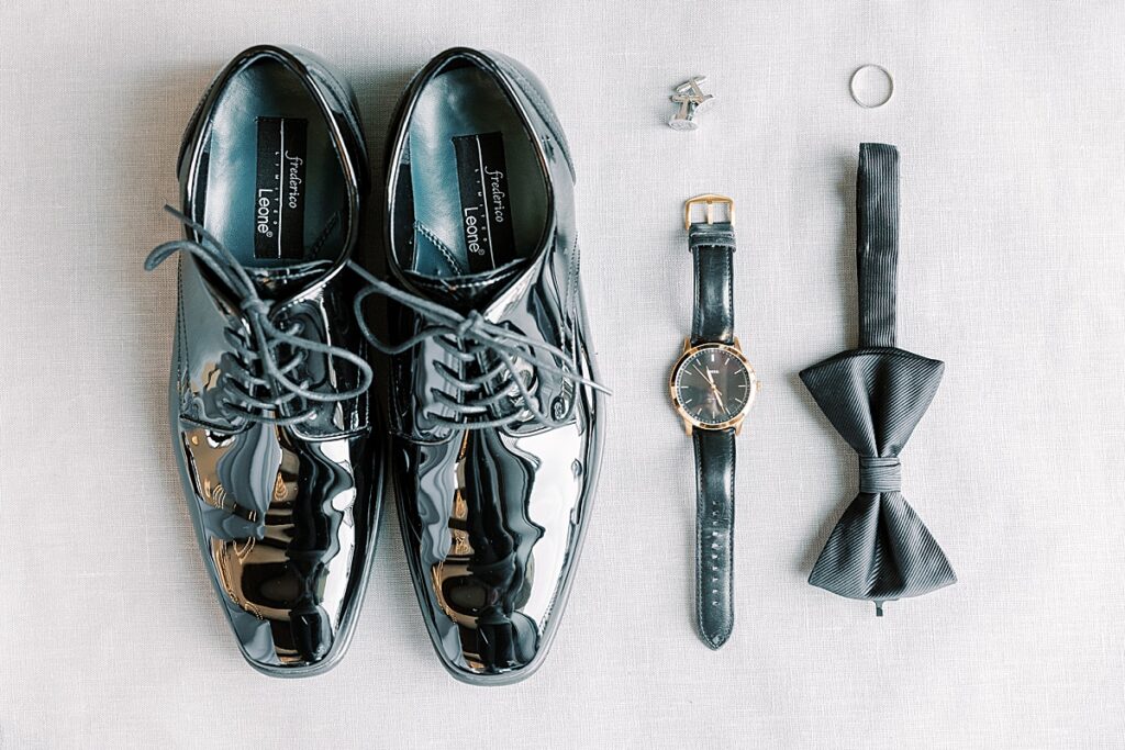 Groom's shoes, cufflinks, ring, watch and bowtie on gray mat