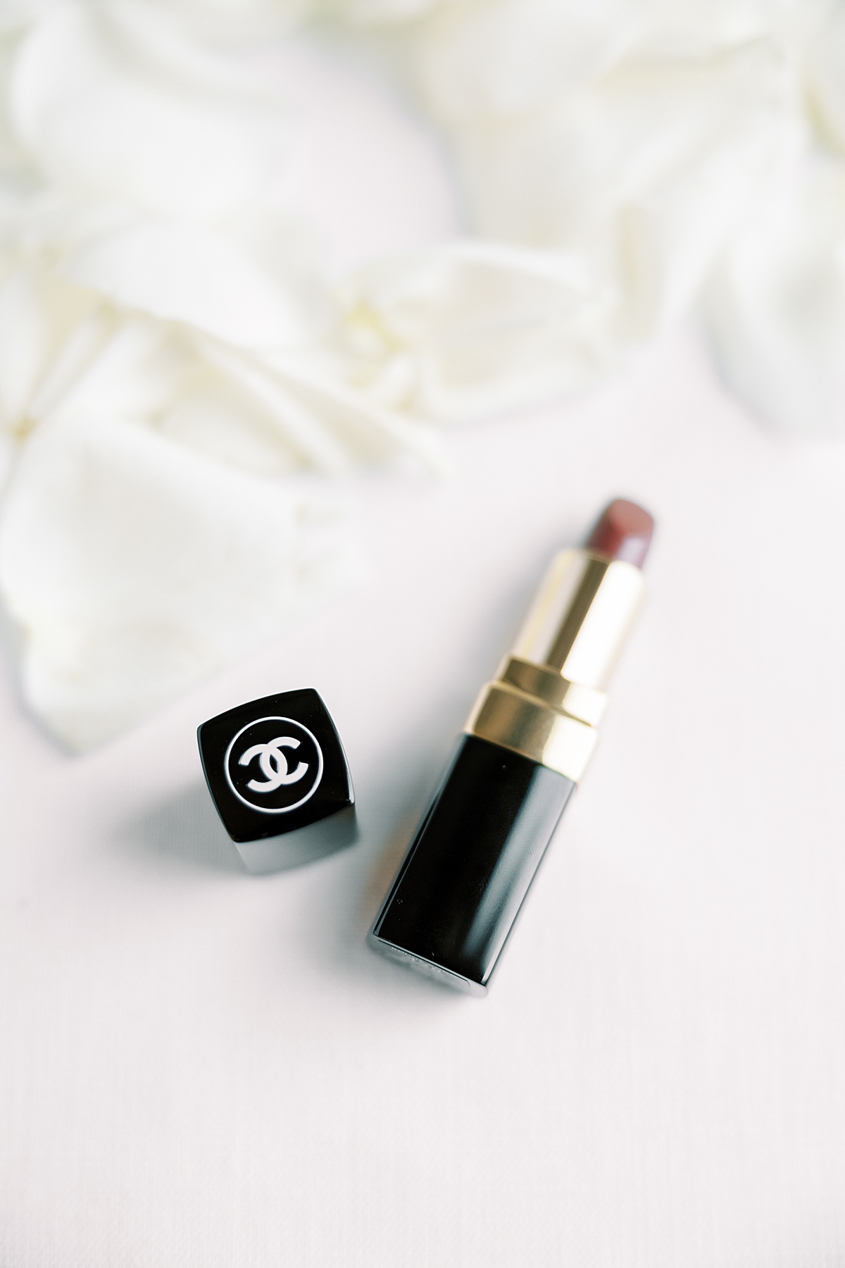 Chanel lipstick laid on white rose petals