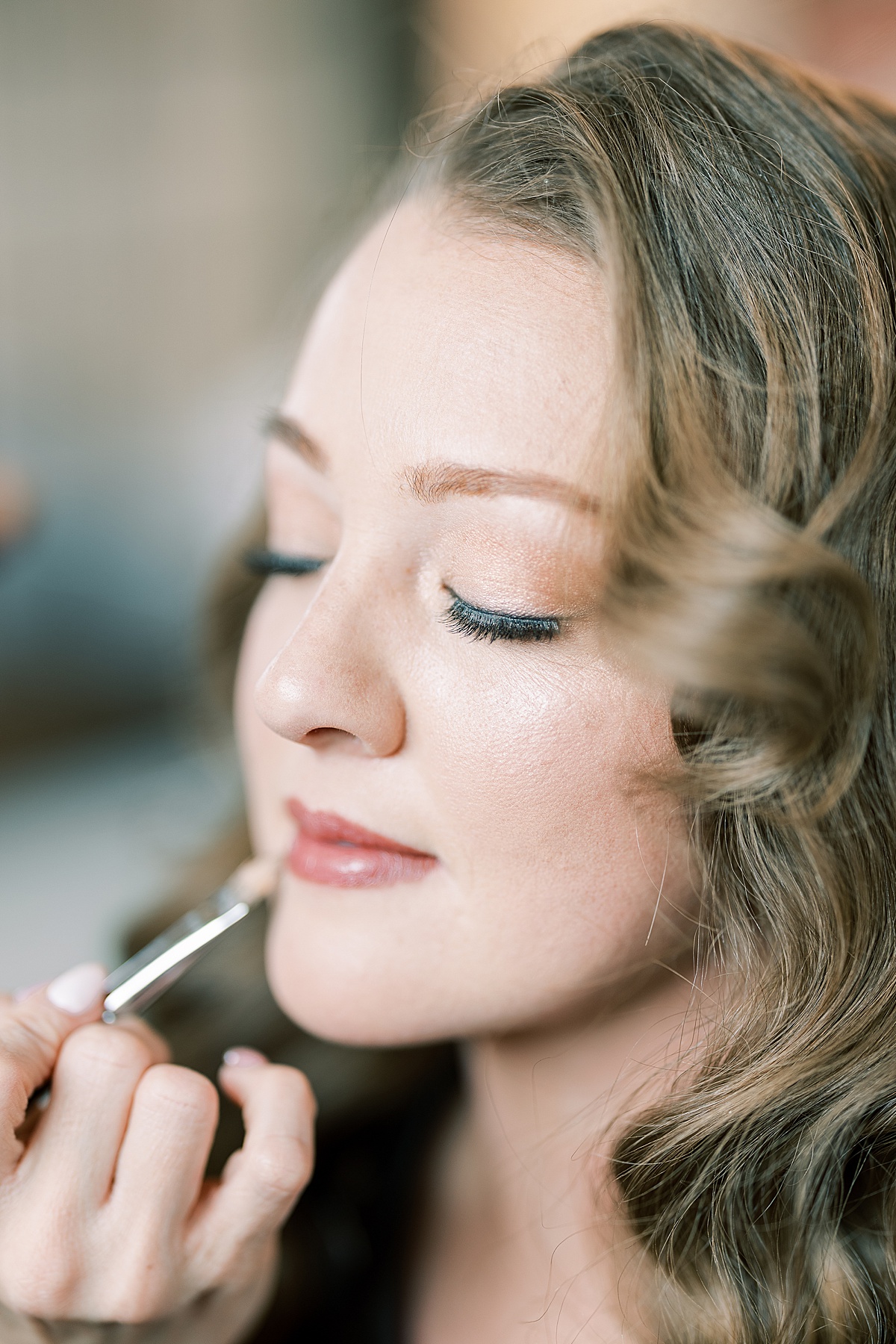 Makeup artist putting lipstick on bride