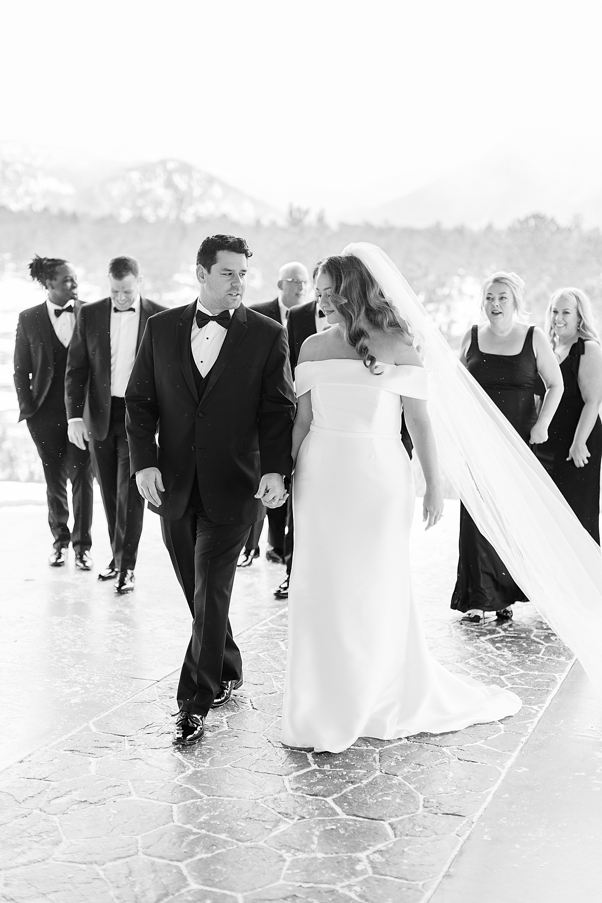 Wedding couple walking with their wedding party on paver walkway