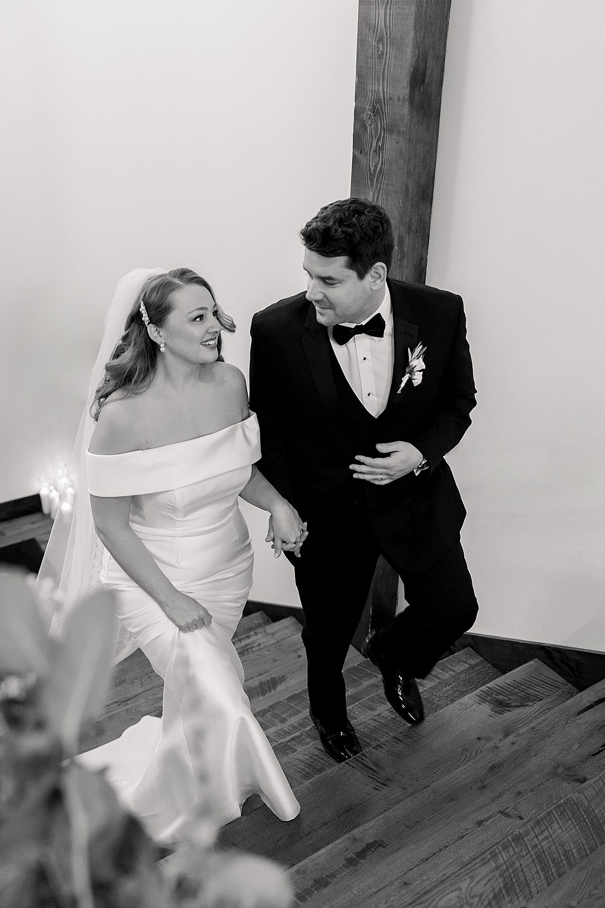 Bride and groom smiling at each other walking up stairs