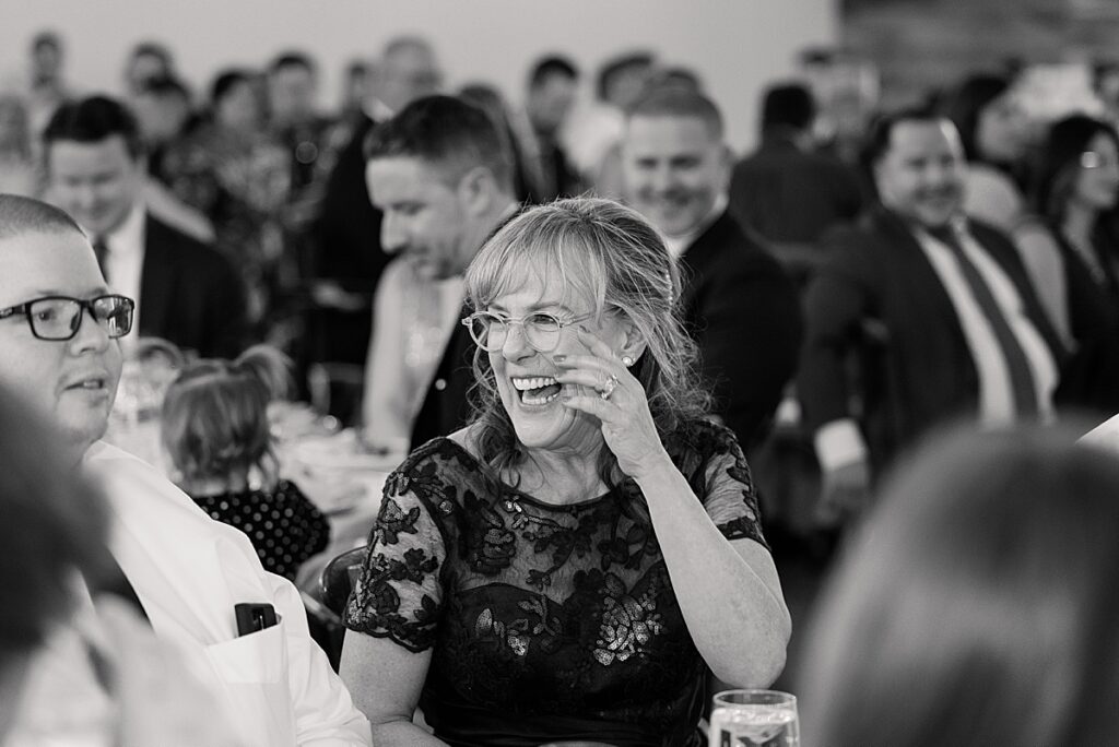 Woman with glasses laughing at wedding speech