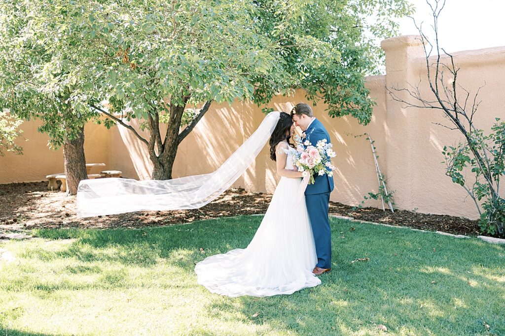 Bride and groom standing together with veil flowing behind them