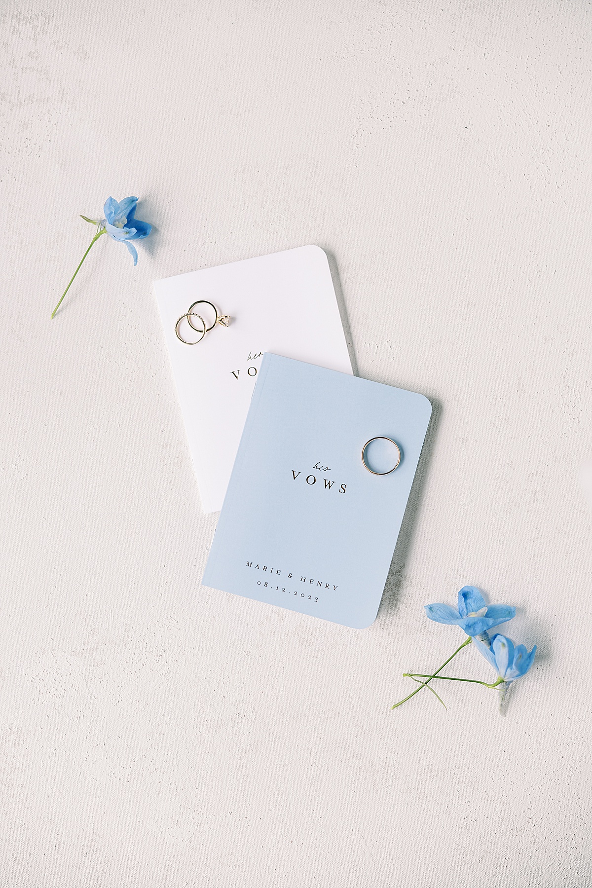 Blue and white vow books surrounded by blue flowers