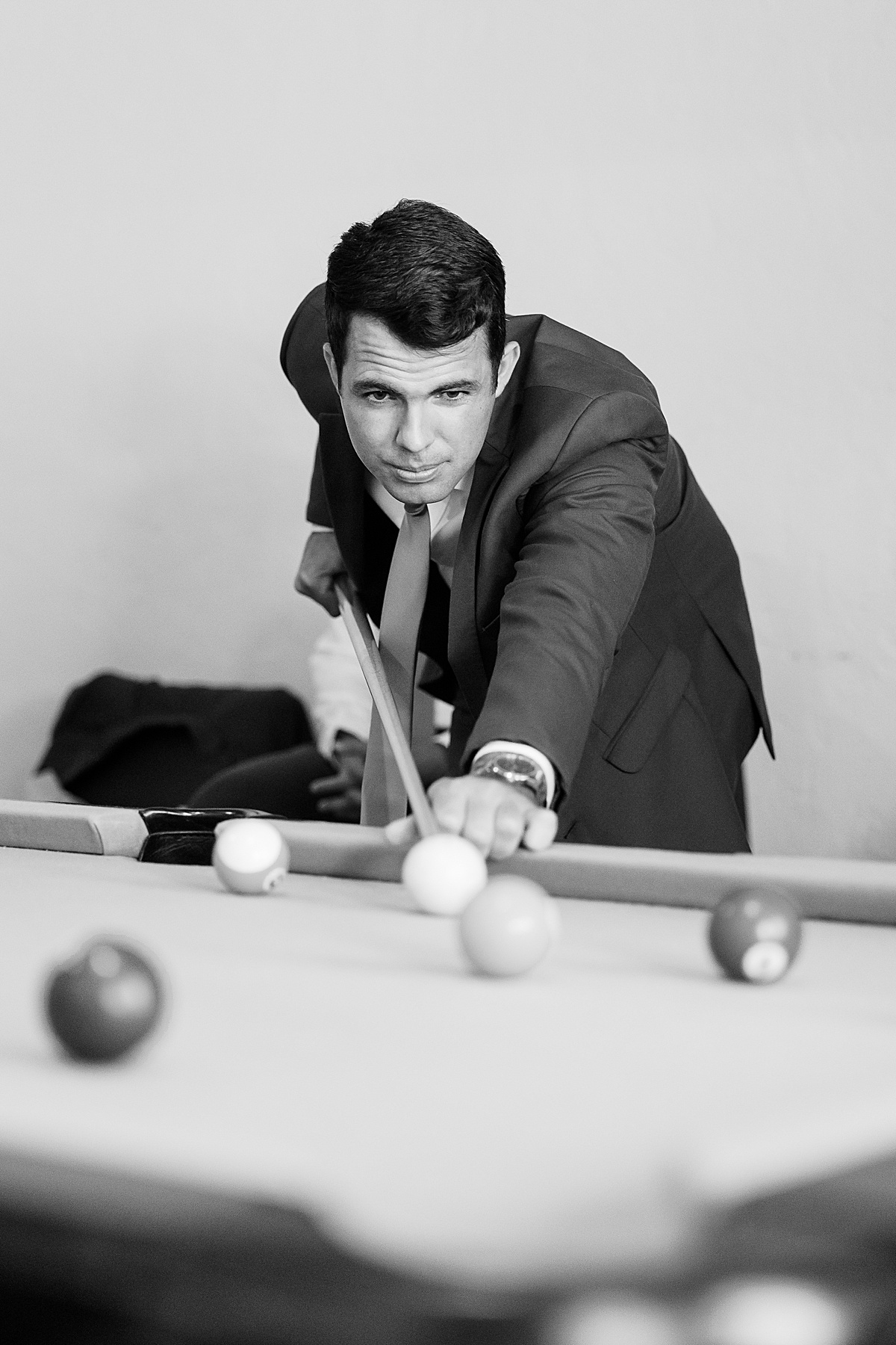 Black and white photo of a man in suit playing pool