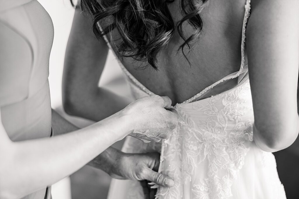 Black and white picture of bride's dress being zipped up