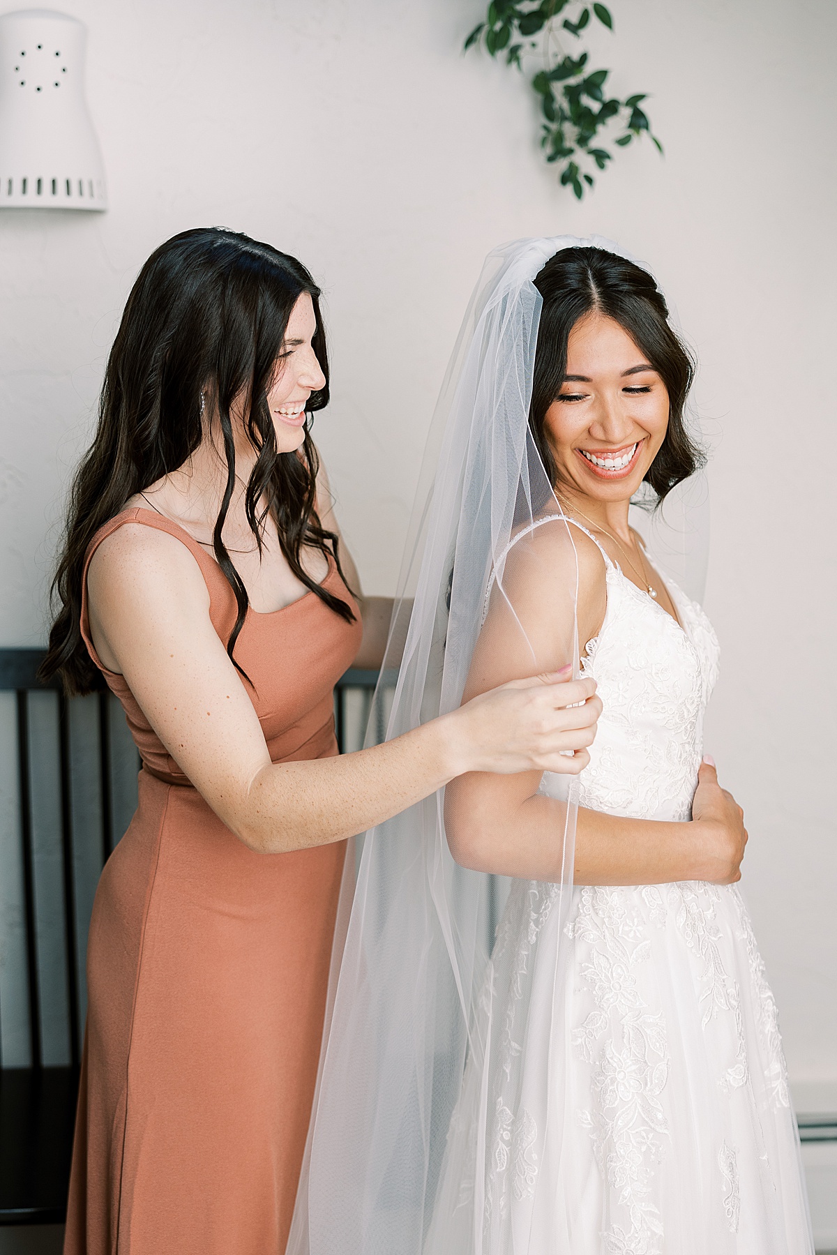 Bridesmaid in pink dress putting on bride's veil