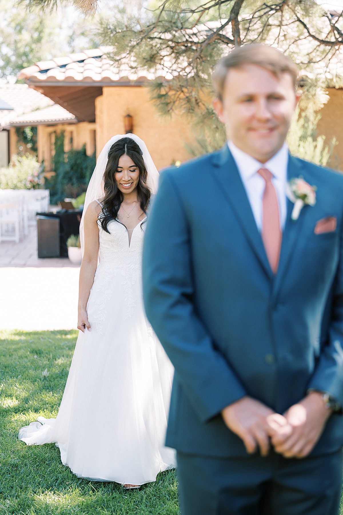 Bride walking up behind groom in blue suit before their first look