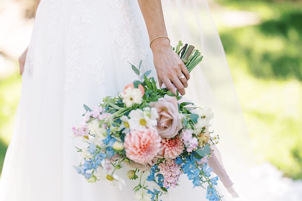 Up close picture of bride holding pink and blue floral bouquet