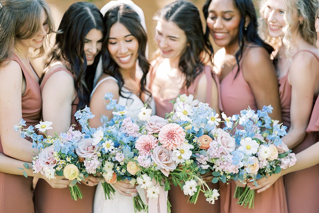 Wedding party huddled together and looking down at their flowers