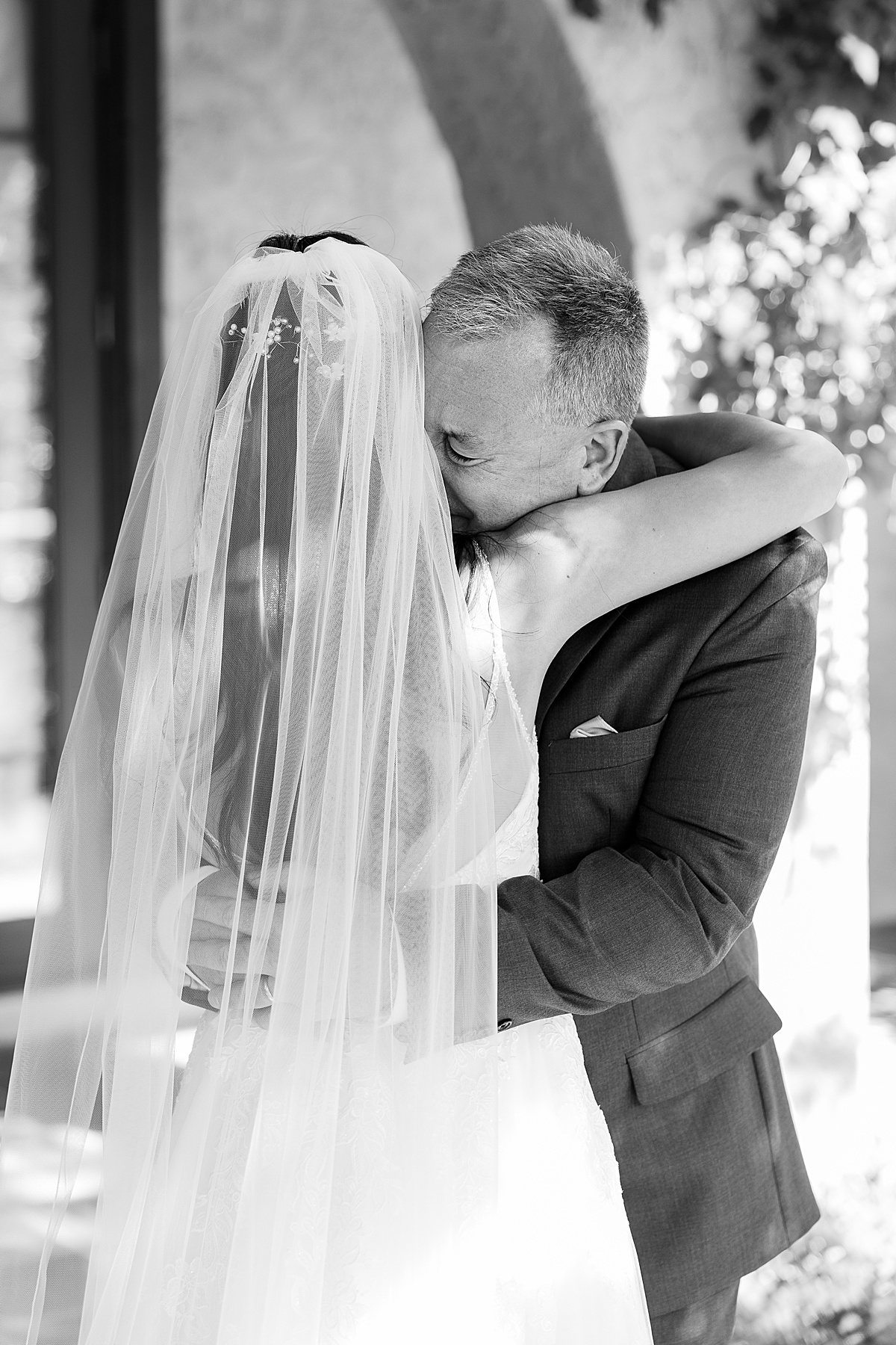 Black and white photo of man hugging bride