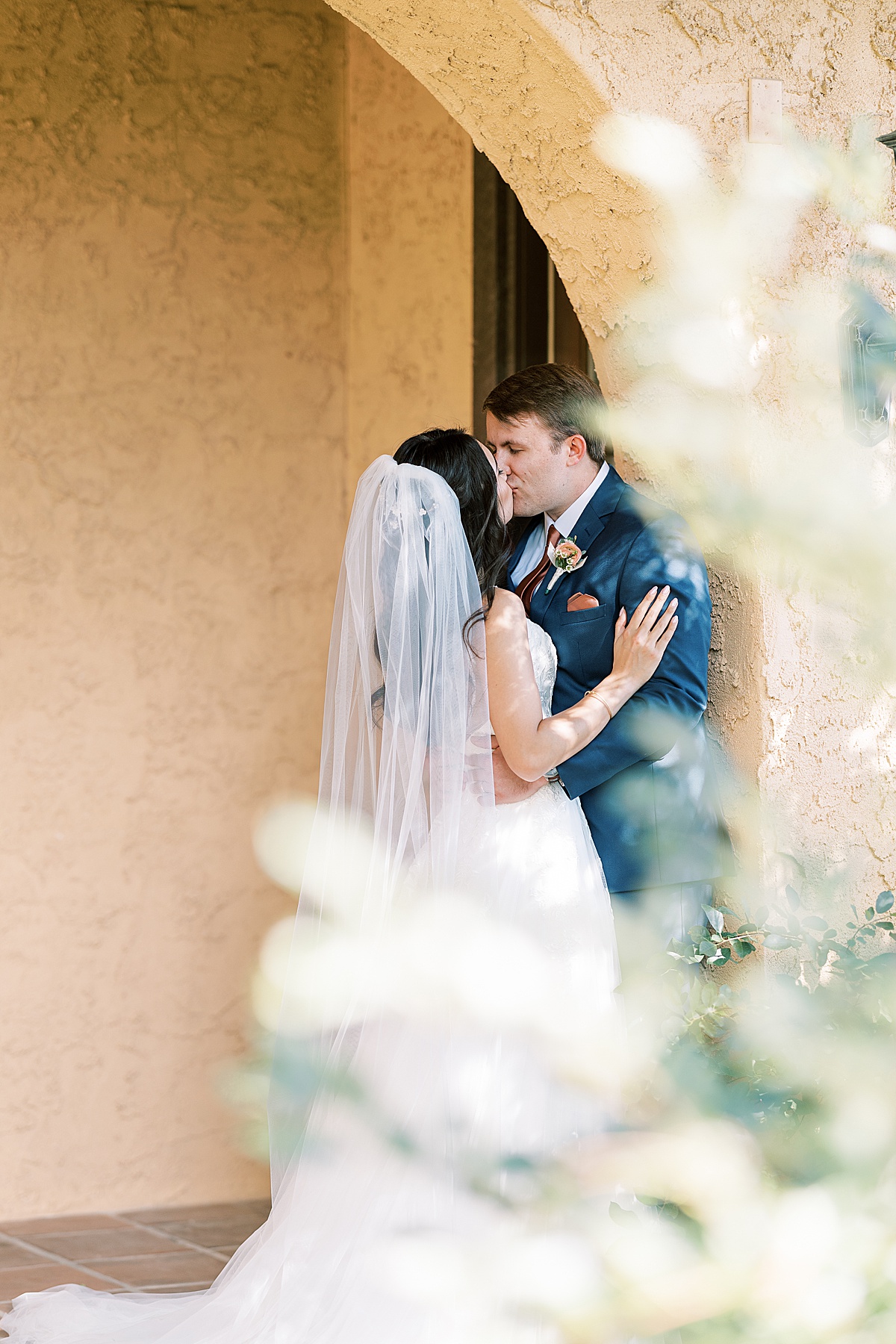 Bride and groom kissing in yellow archway