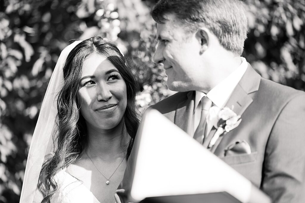 Black and white photo of bride looking up at groom during wedding ceremony