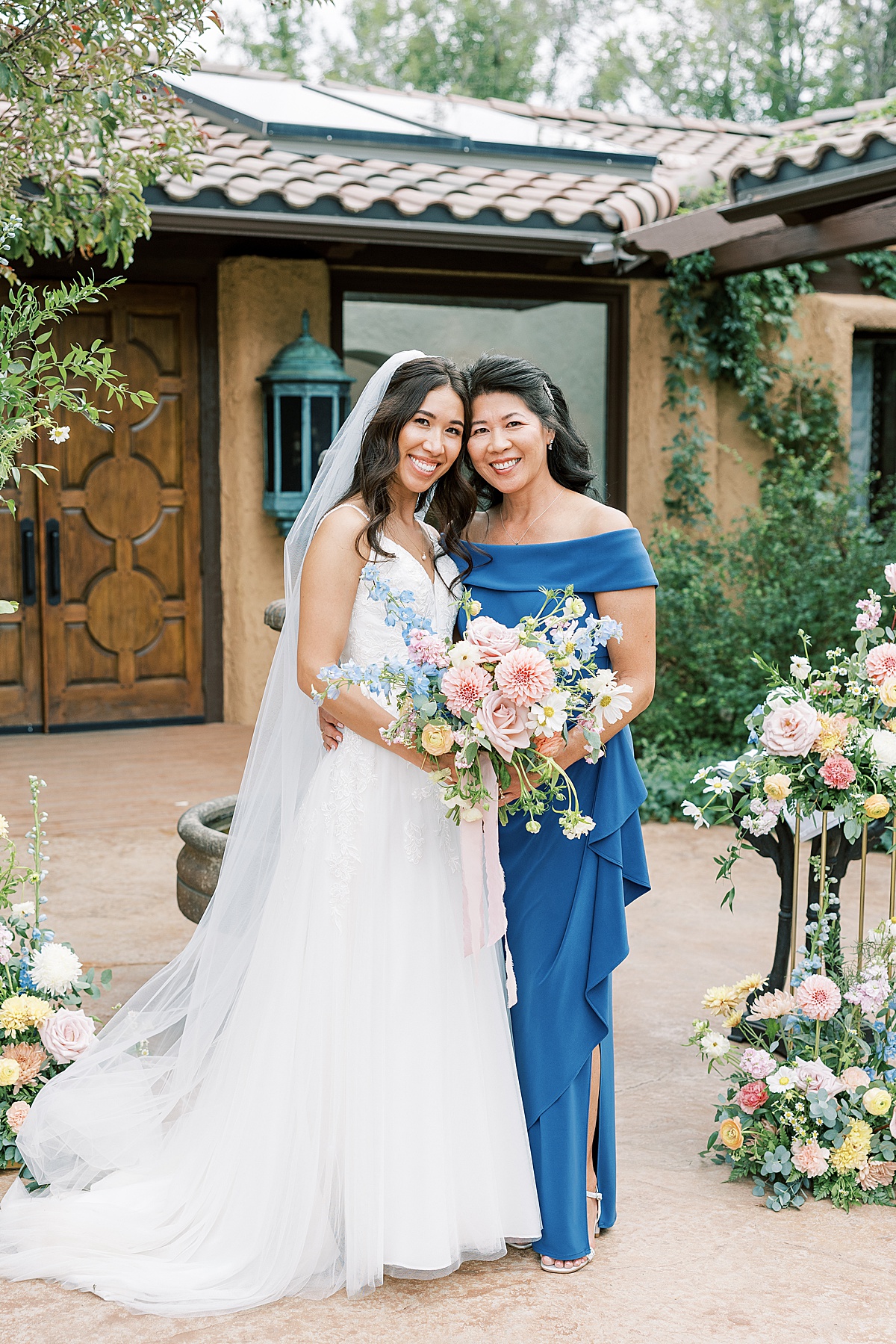 Bride and mom in blue dress posing together for portrait