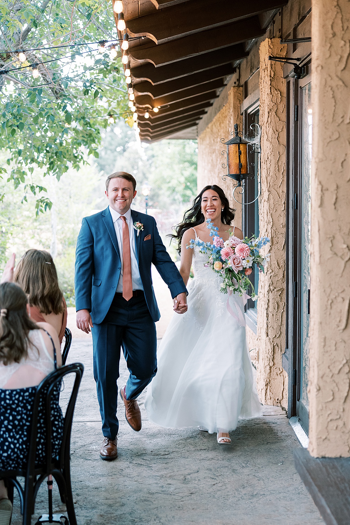 Bride and groom smiling and running into wedding reception