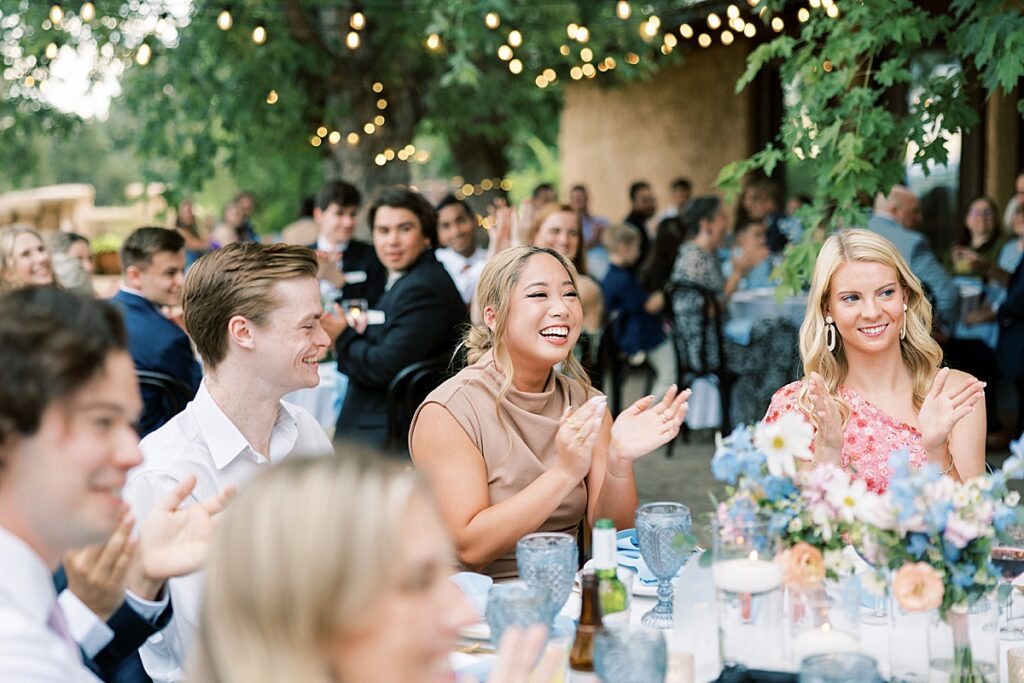 Wedding guest clapping at table surrounded by other guests