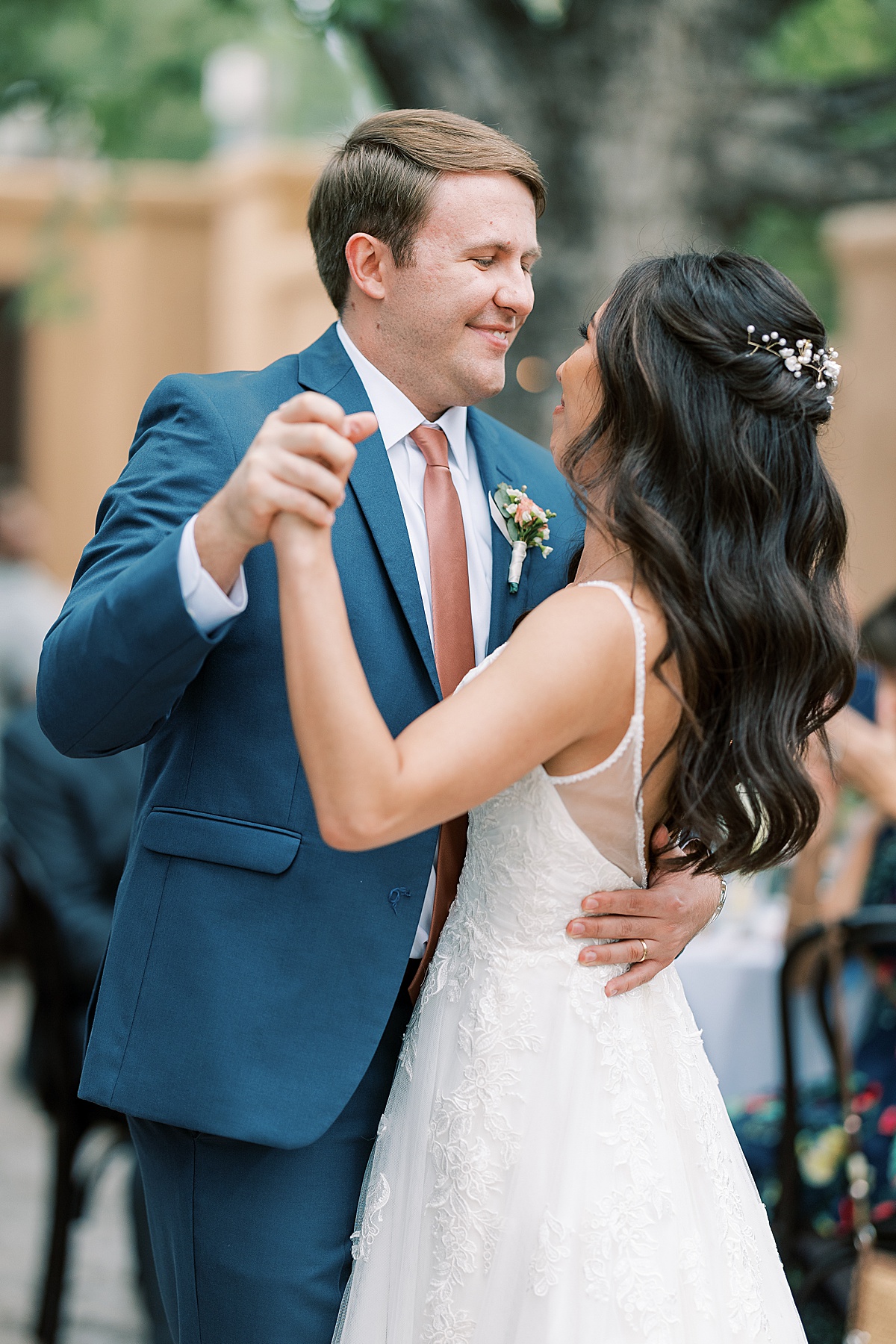 Man in blue suit smiling at bride while dancing