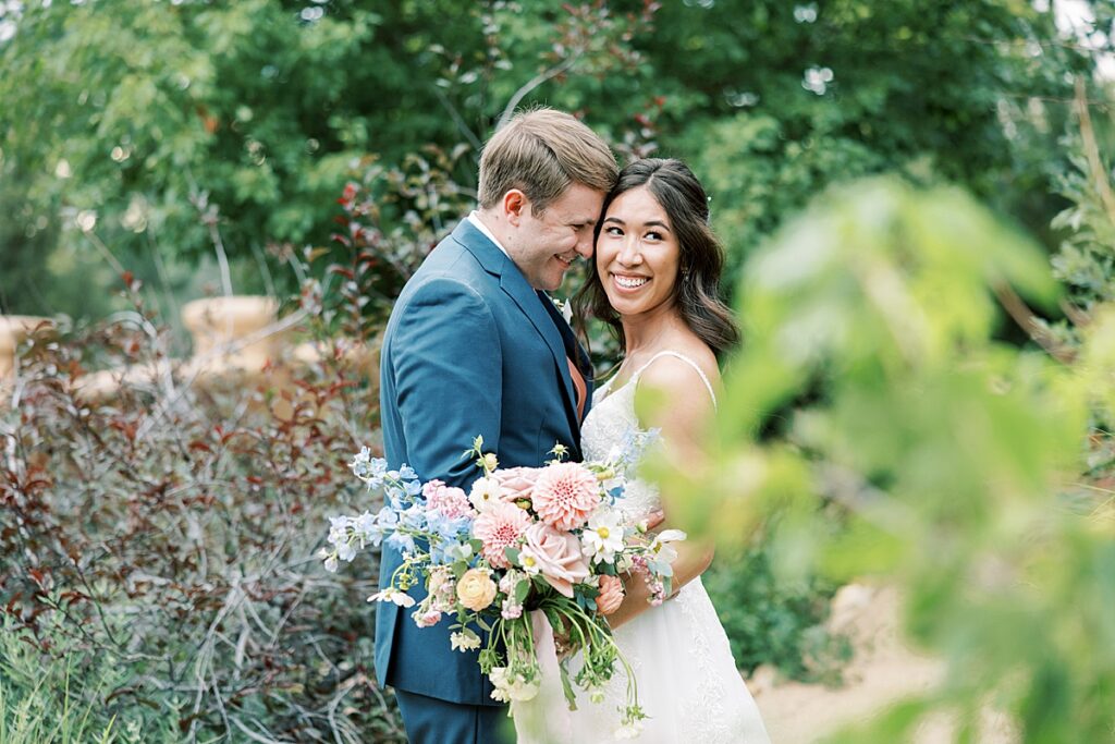 Couple poses slightly behind a bush during wedding portraits