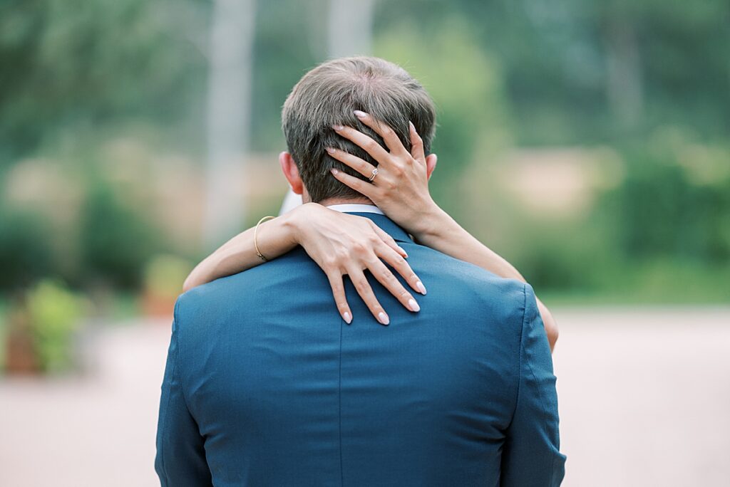 Back of groom's head with bride's hands showing off wedding ring