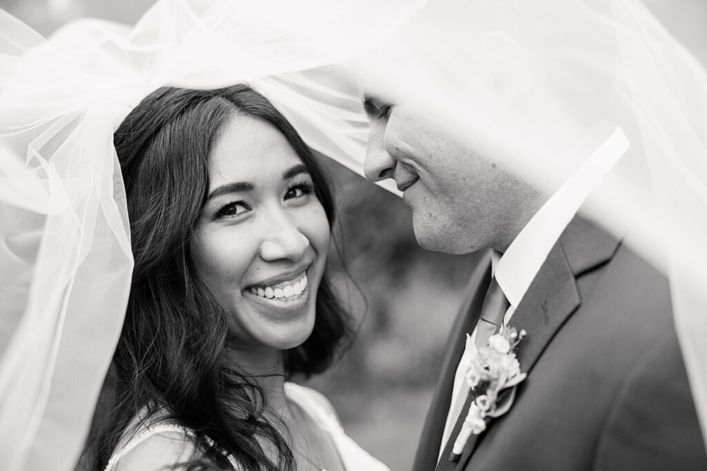 Black and white photo of a woman under veil smiling towards the camera