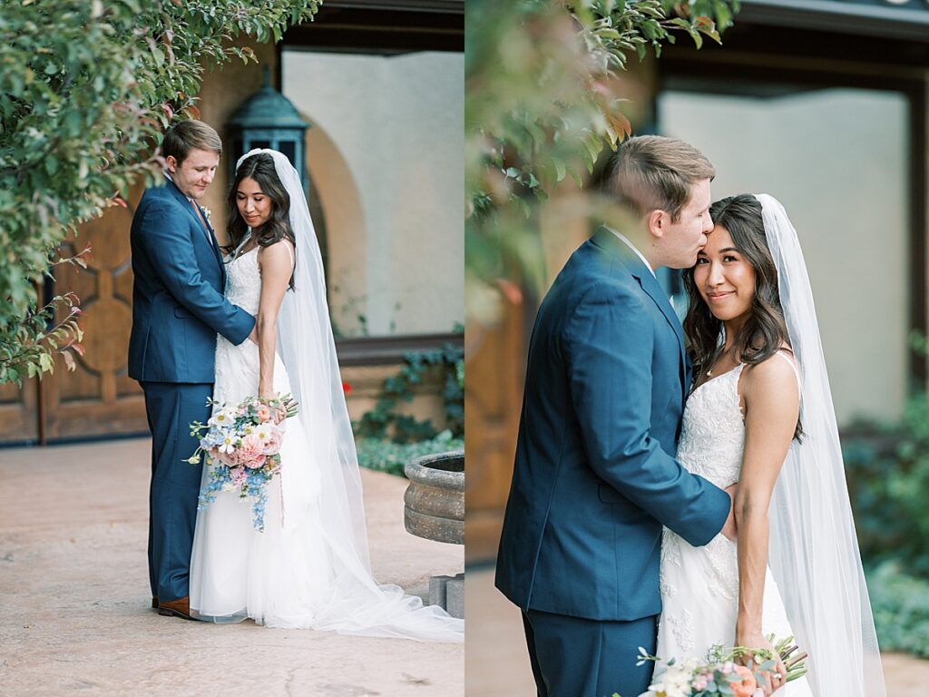 Bride and groom standing chest to chest looking down at flowers