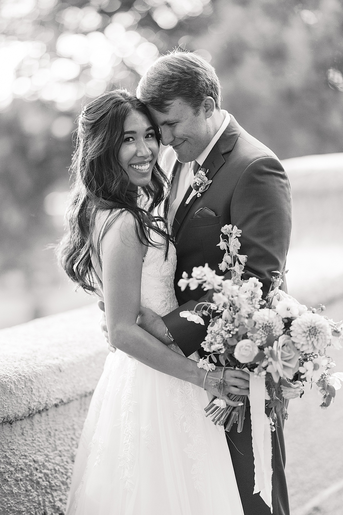 Black and white photo of bride and groom in front of a wall