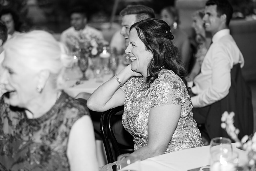 Black and white photo of wedding guest smiling from the side