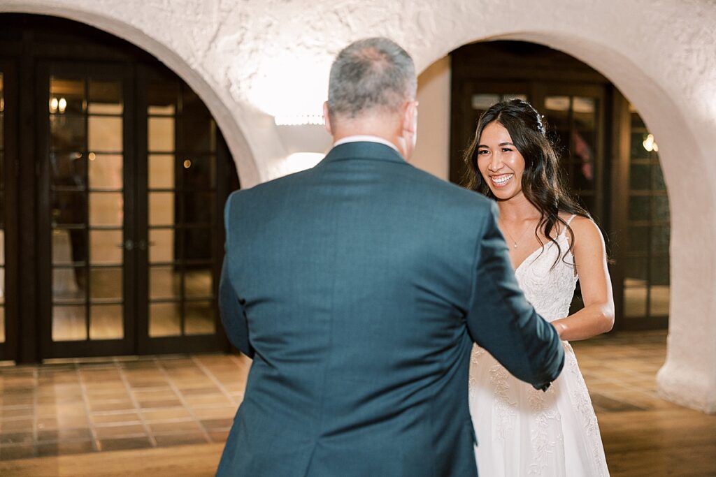 Bride in white dress dances with Dad in gray suit