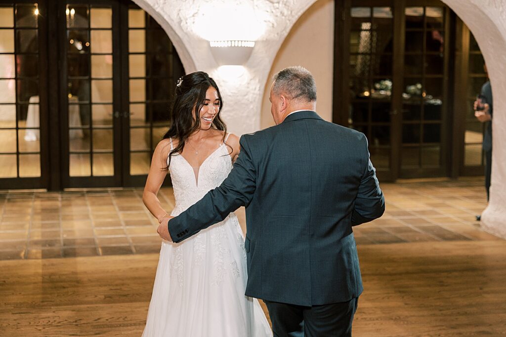 Bride in white dress dances with Dad in gray suit