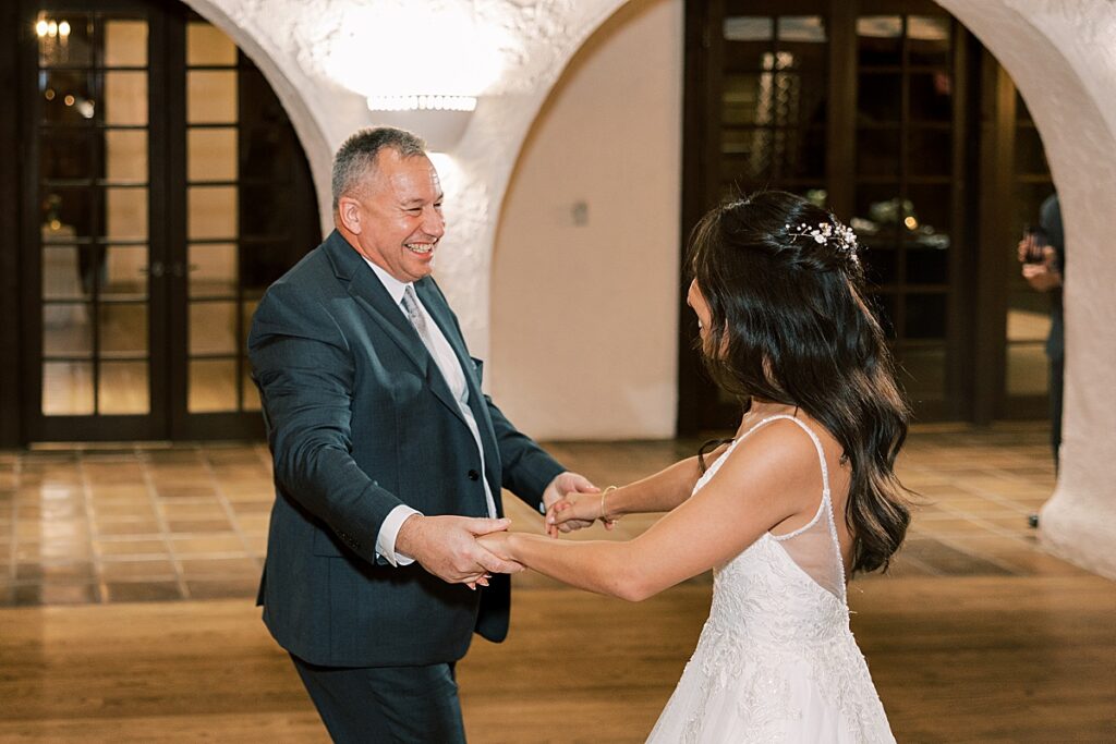 Bride in white dress dances with Dad in gray suit