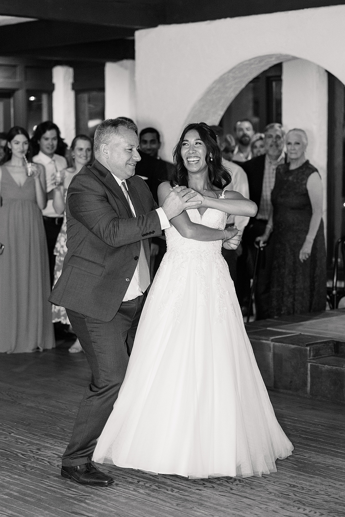 Bride in white dress dances with Dad in gray suit