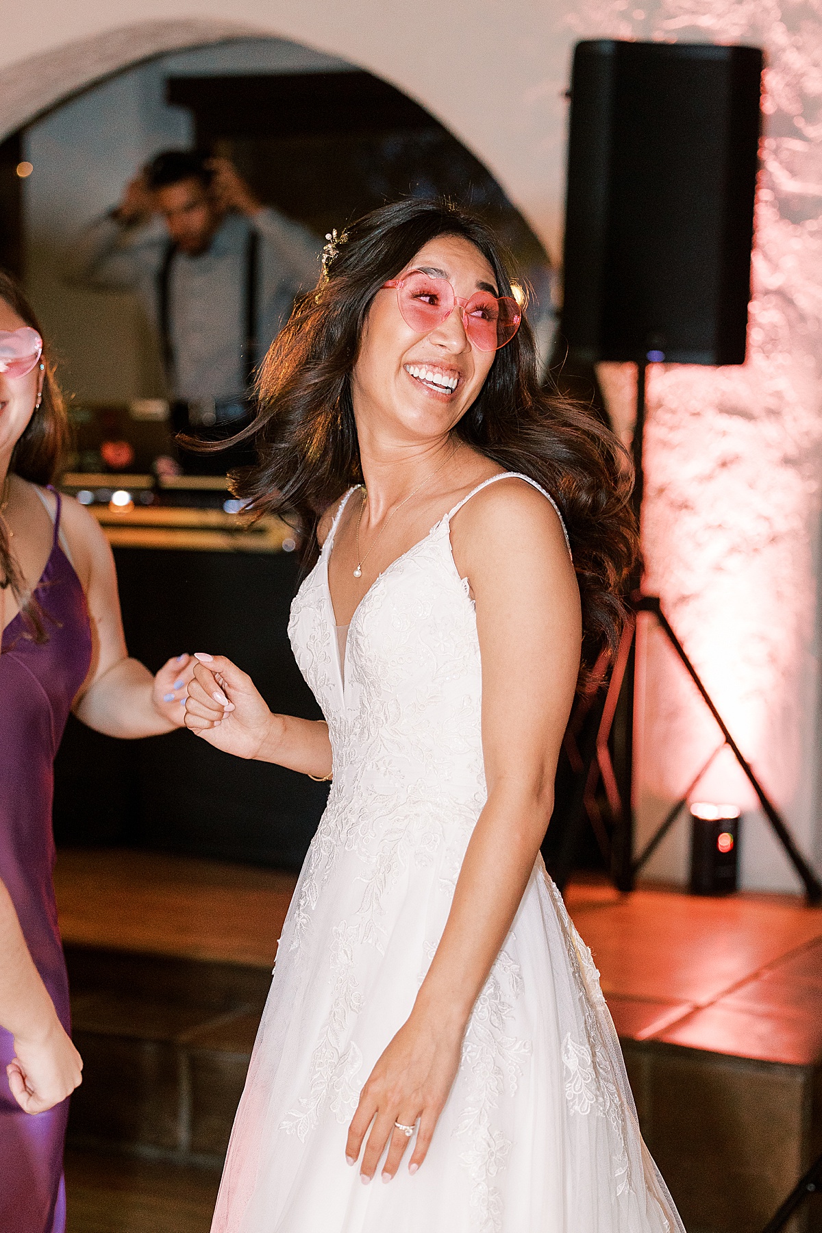 Bride in pink heart sunglasses smiling back over her shoulder