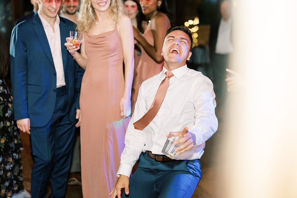 Wedding guest in white shirt and orange tie dances