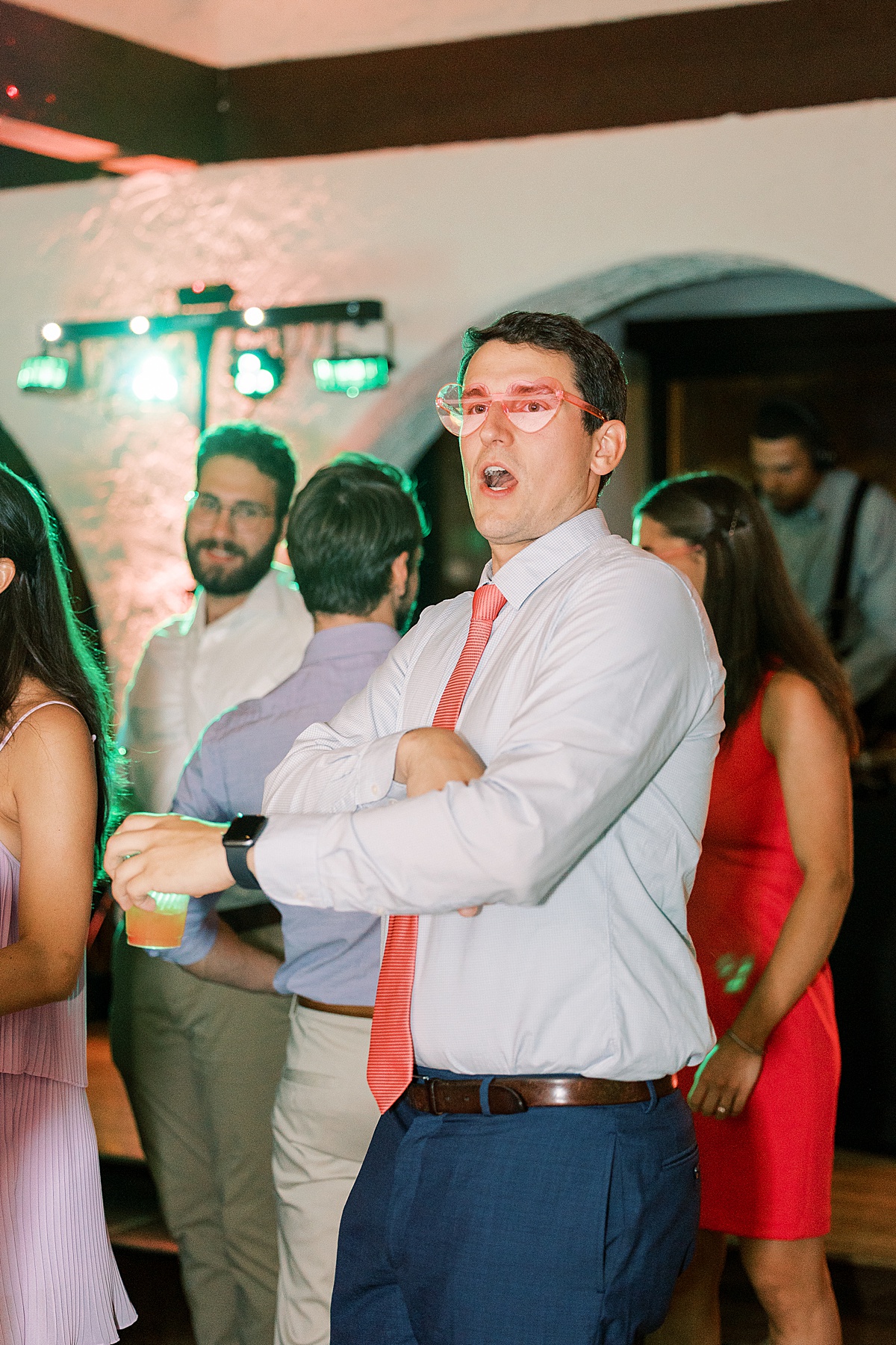 Man in pink sunglasses with pink tie dancing at wedding reception